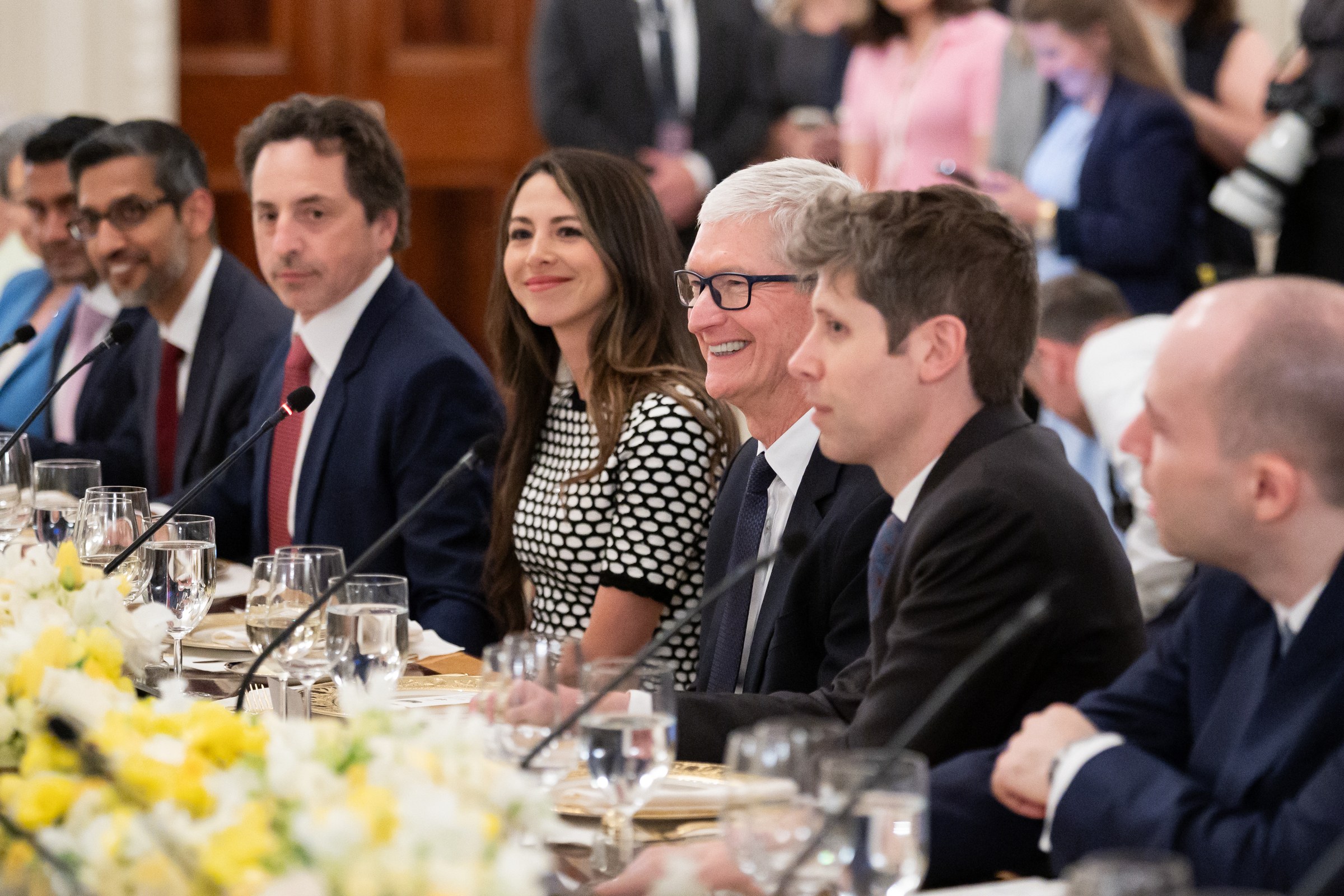 Sam Altman, in a dark jacket, sits at a long dinner table in the White House State Dining Room among other guests.