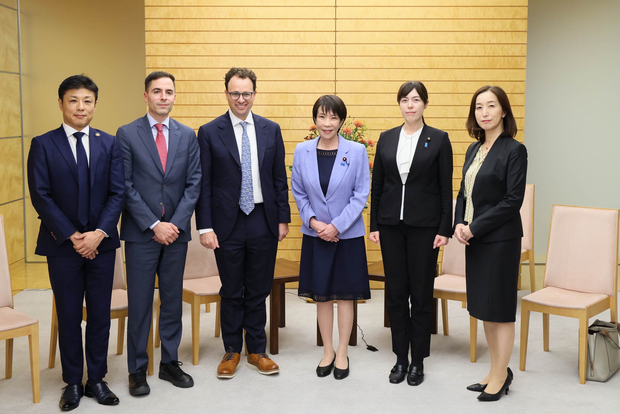 Dario Amodei stands with Prime Minister Sanae Takaichi and four others in a reception room in Tokyo.